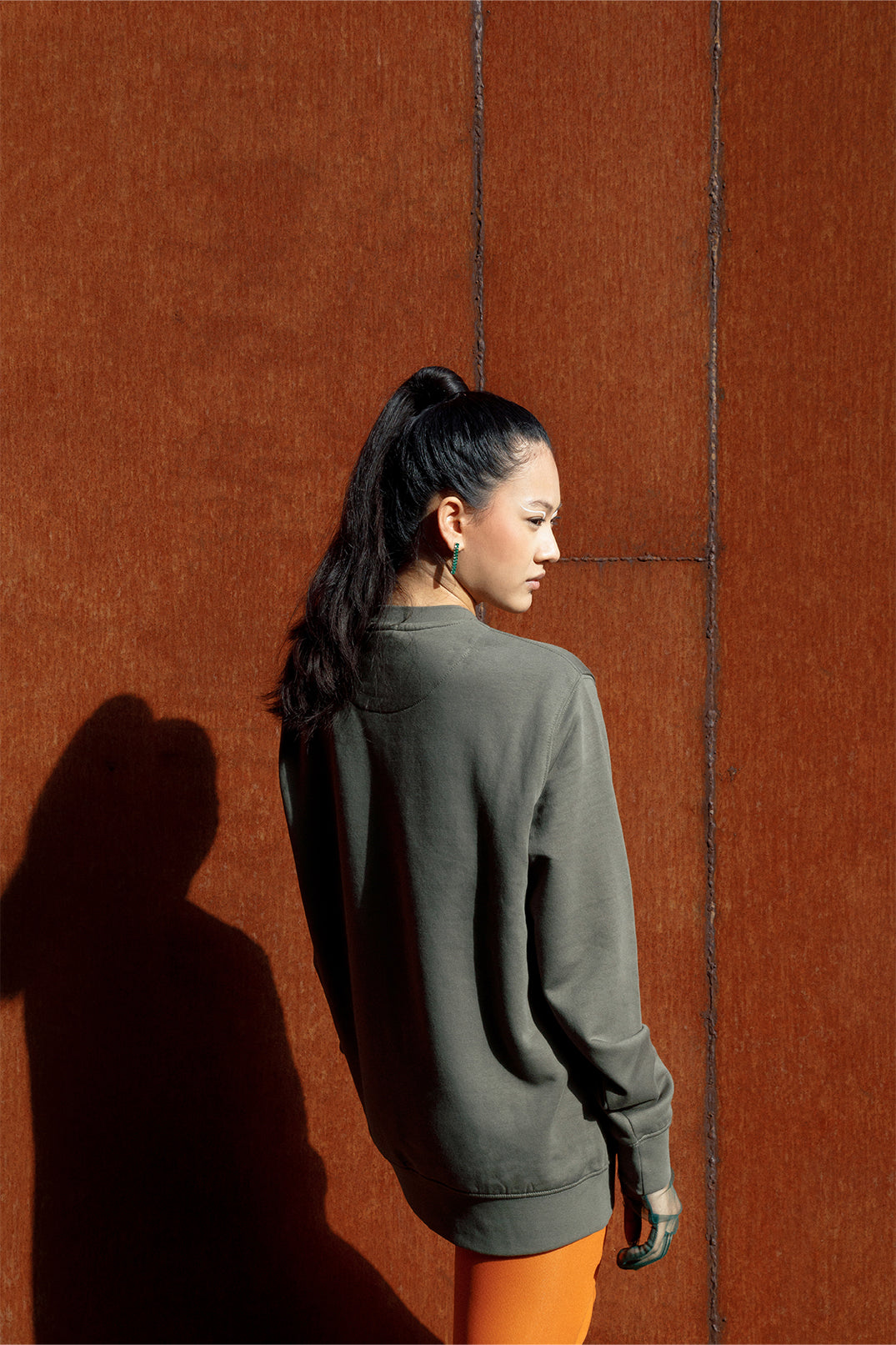 Back of the oversized unisex green sweatshirt worn by a model, showing smooth fabric and stitching.