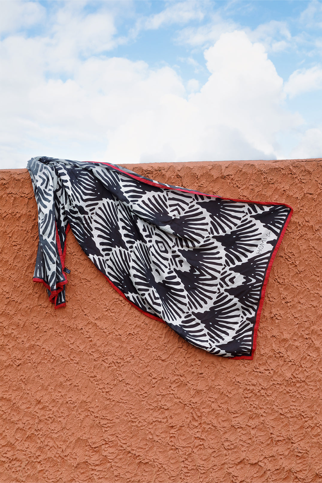 Scarf 70×180 cm in modal-cashmere blend with black and white fan motif, red border.