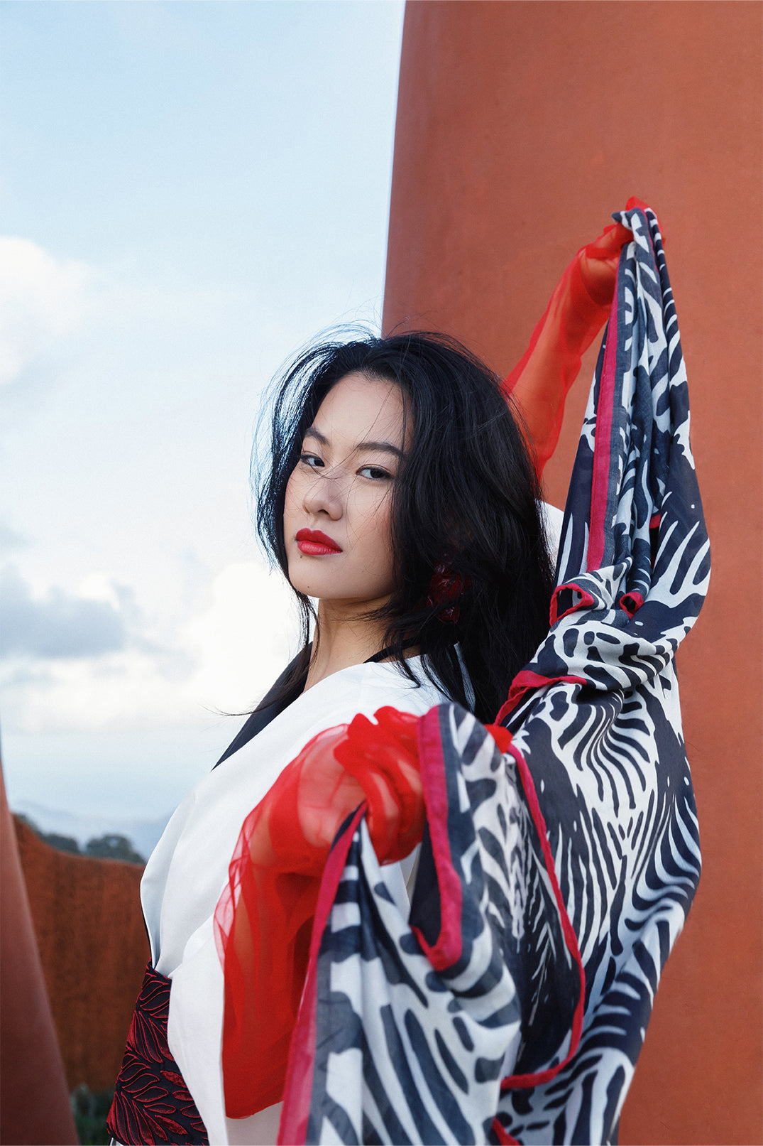 Scarf 70×180 cm in modal-cashmere blend with black and white fan motif, red border held by a model.