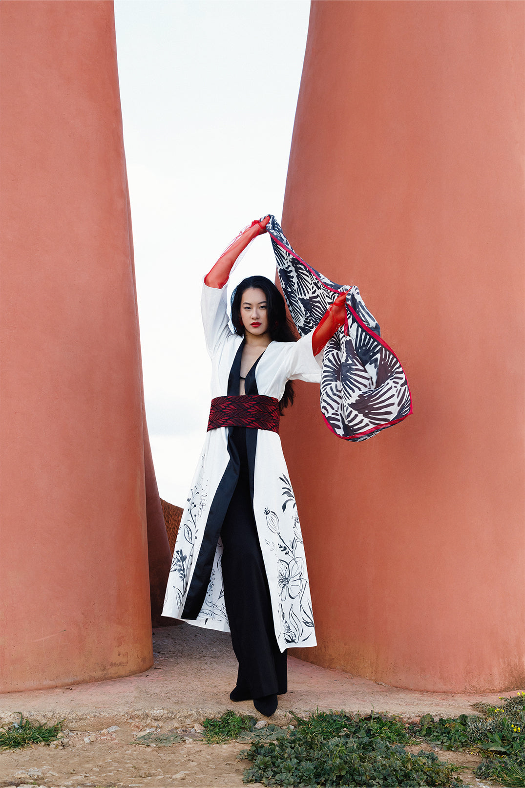 White long stretch cotton kimono worn by a model, featuring elegant hand-painted floral illustration directly on the fabric, with a brocade belt at the waist for a fluid and sophisticated silhouette.