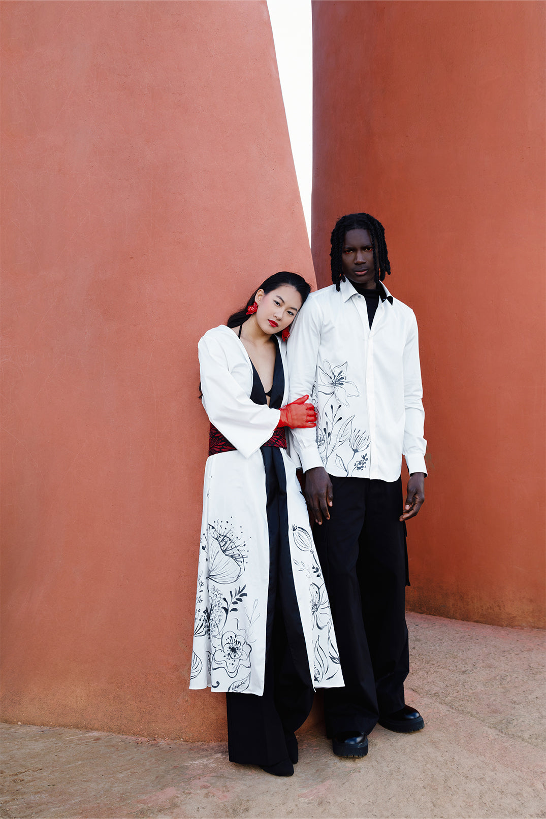 White long stretch cotton kimono worn by a model, featuring elegant hand-painted floral illustration directly on the fabric, with a brocade belt at the waist for a fluid and sophisticated silhouette.