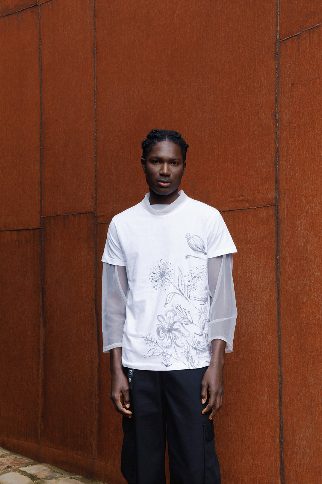 White unisex oversized T-shirt worn by a model, featuring hand-painted black flowers decorating the entire left side of the garment.
