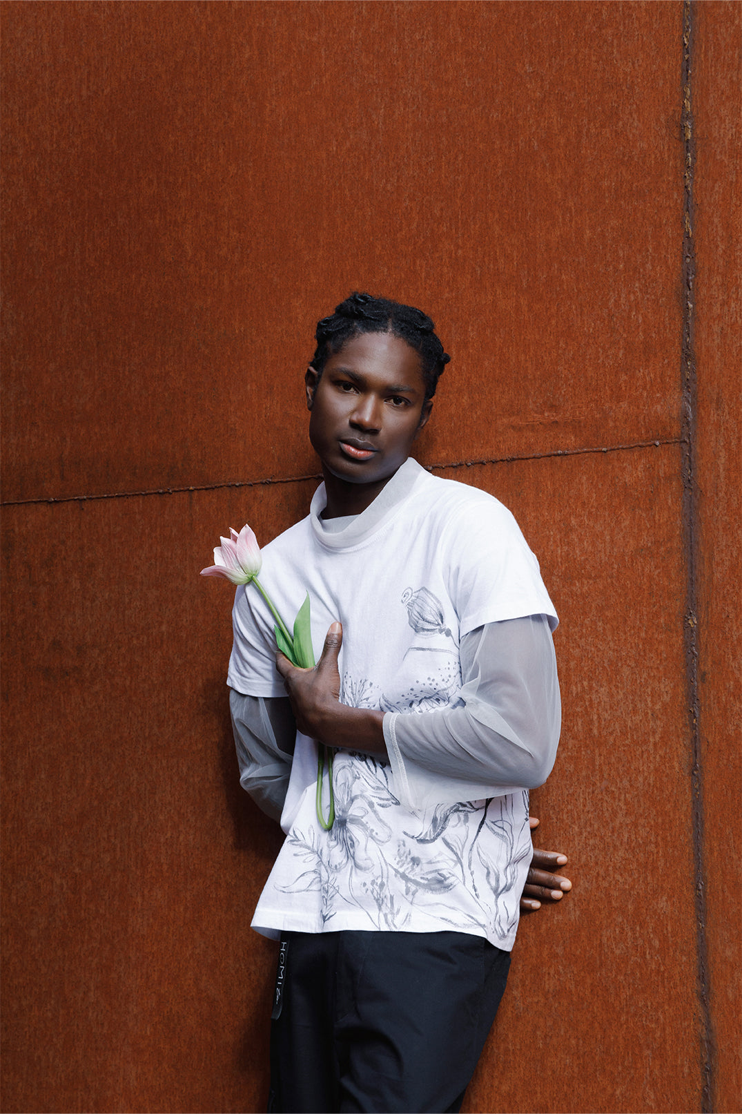 White unisex oversized T-shirt worn by a model, featuring hand-painted black flowers decorating the entire left side of the garment.