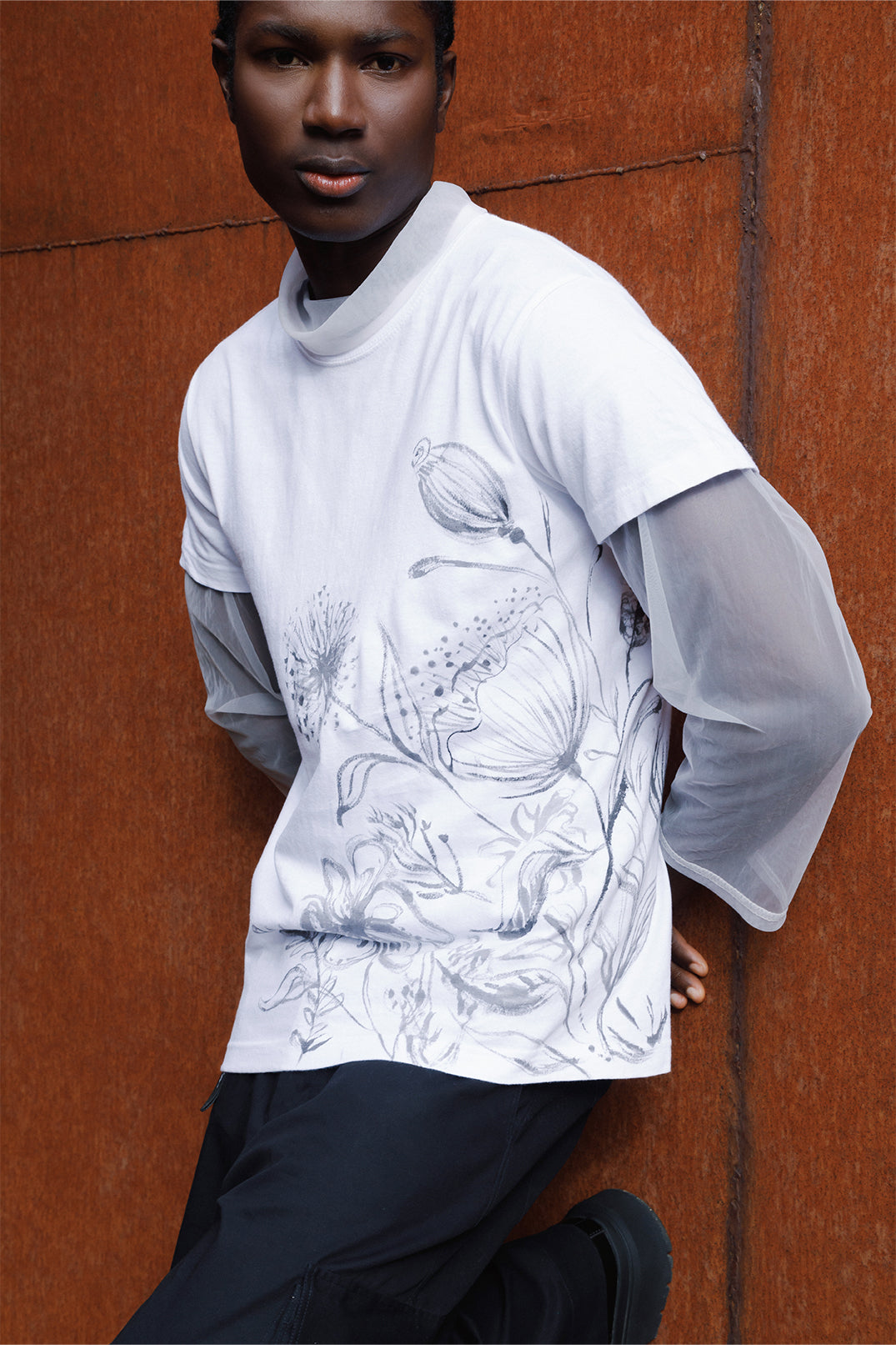 Side view of the white unisex oversized T-shirt worn by a model, featuring hand-painted black flowers decorating the entire left side of the garment.