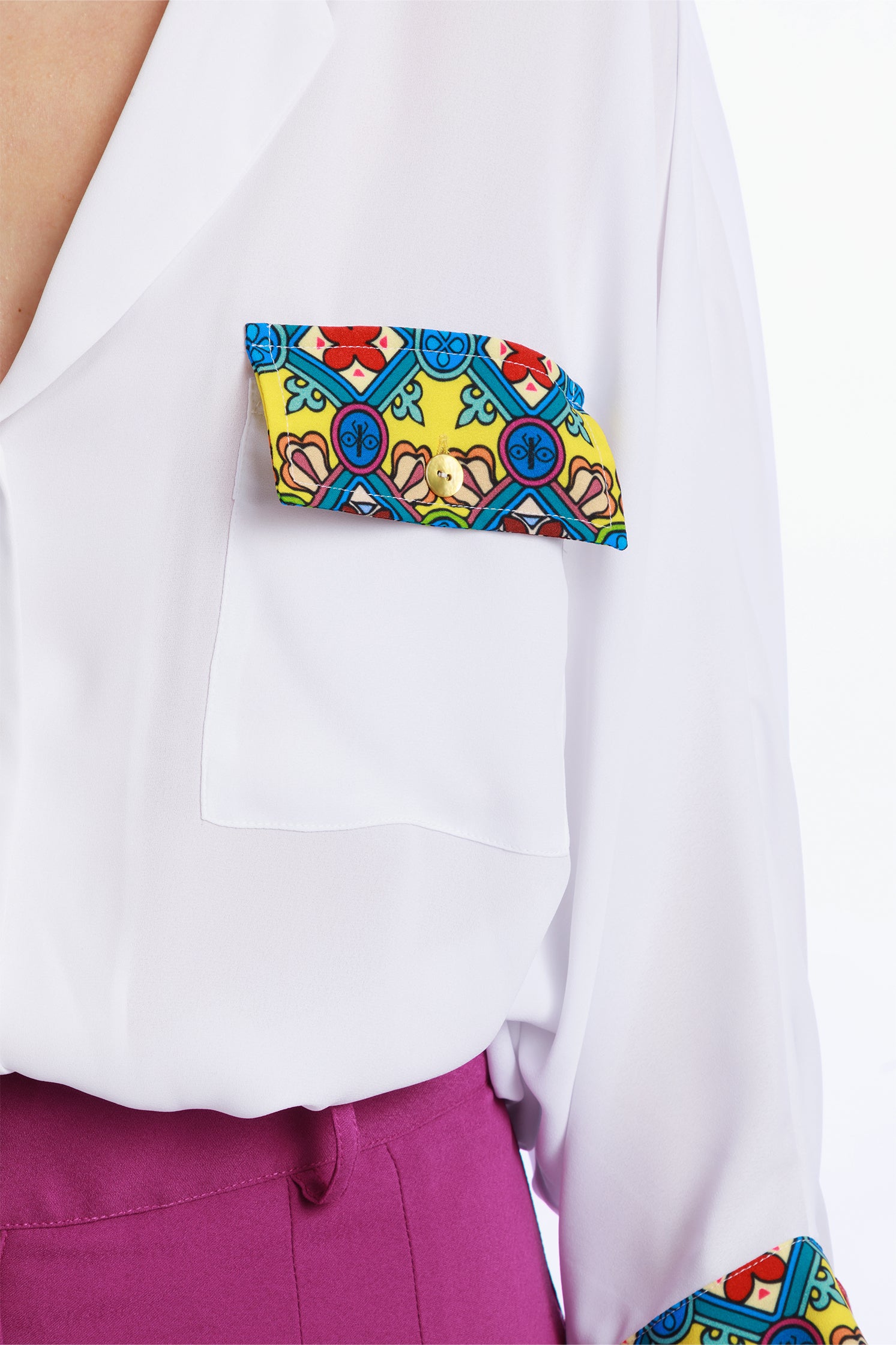 Close-up of the printed detail on the pocket of the white oversize blouse, highlighting artistic patterns and craftsmanship.