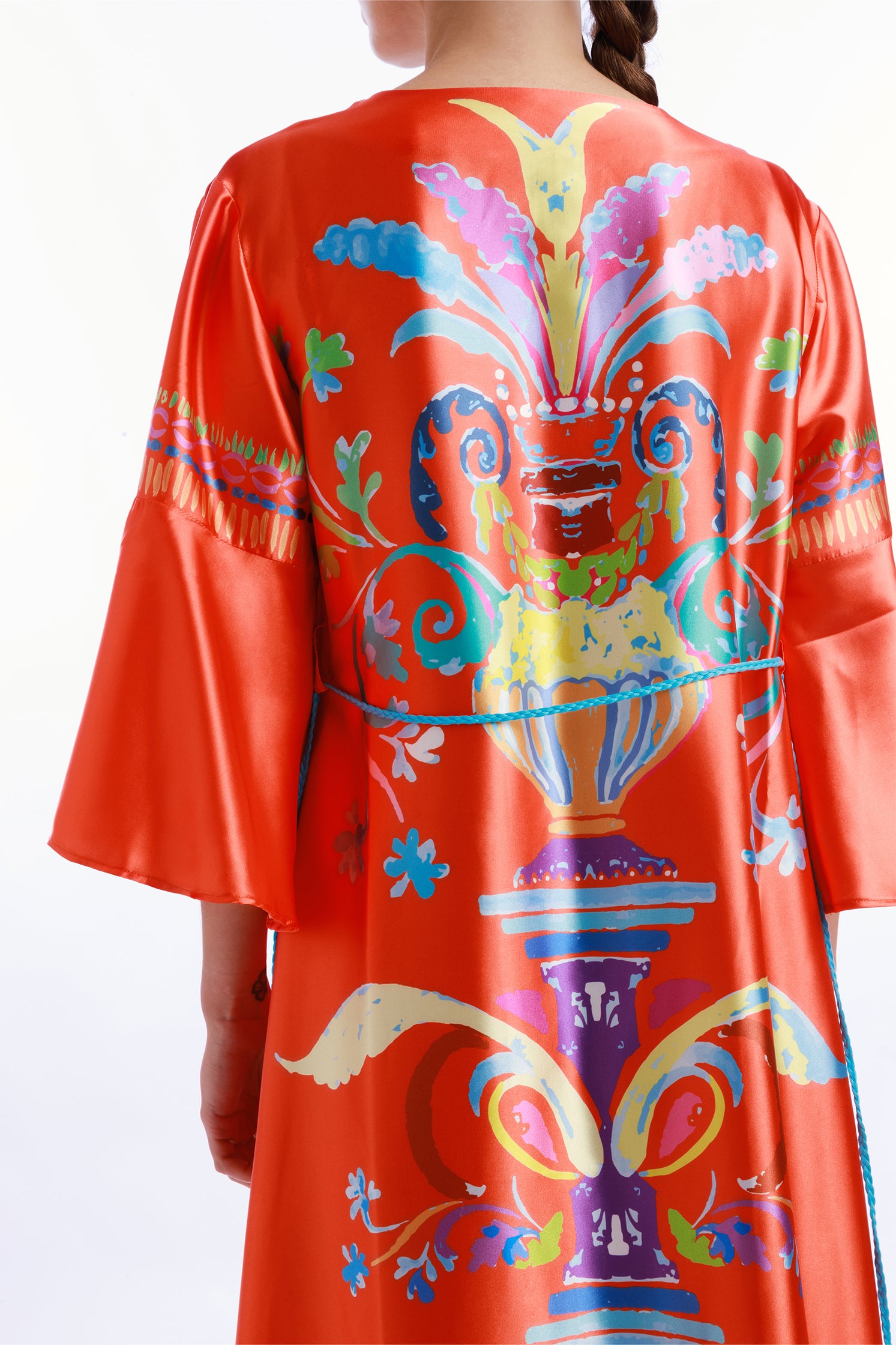 Close-up of the colorful majolica-inspired print covering the back of the long caftan, showing intricate patterns, vibrant chromatic details and artistic motifs.