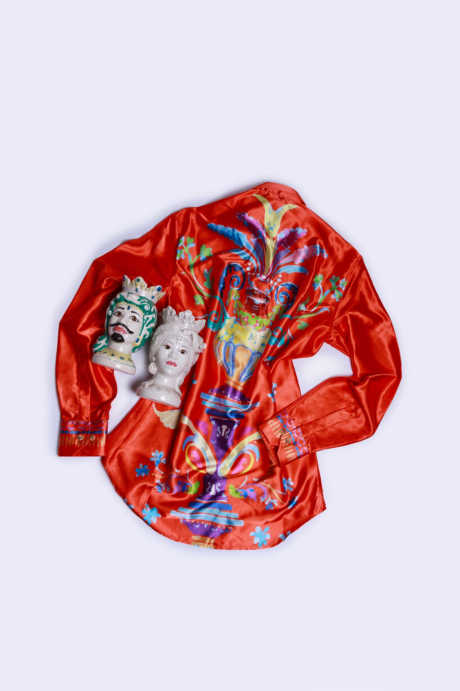 Back view of the long-sleeved shirt made of soft and shiny fabric, featuring an exclusive pattern on the back with a red-orange background and turquoise embroidery on the heart side.