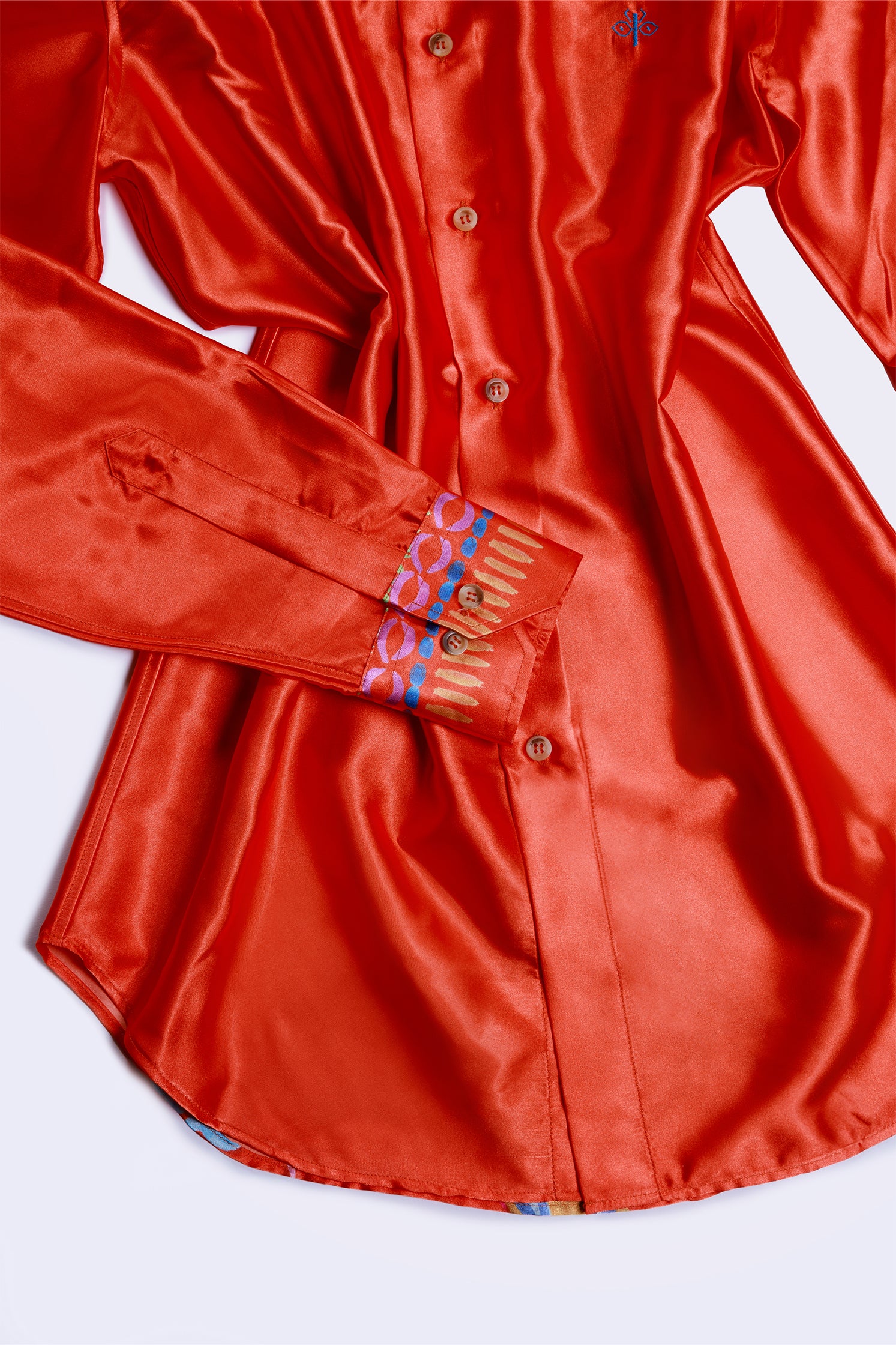 Close-up of the exclusive pattern on the cuff of the shirt in vibrant red-orange background.