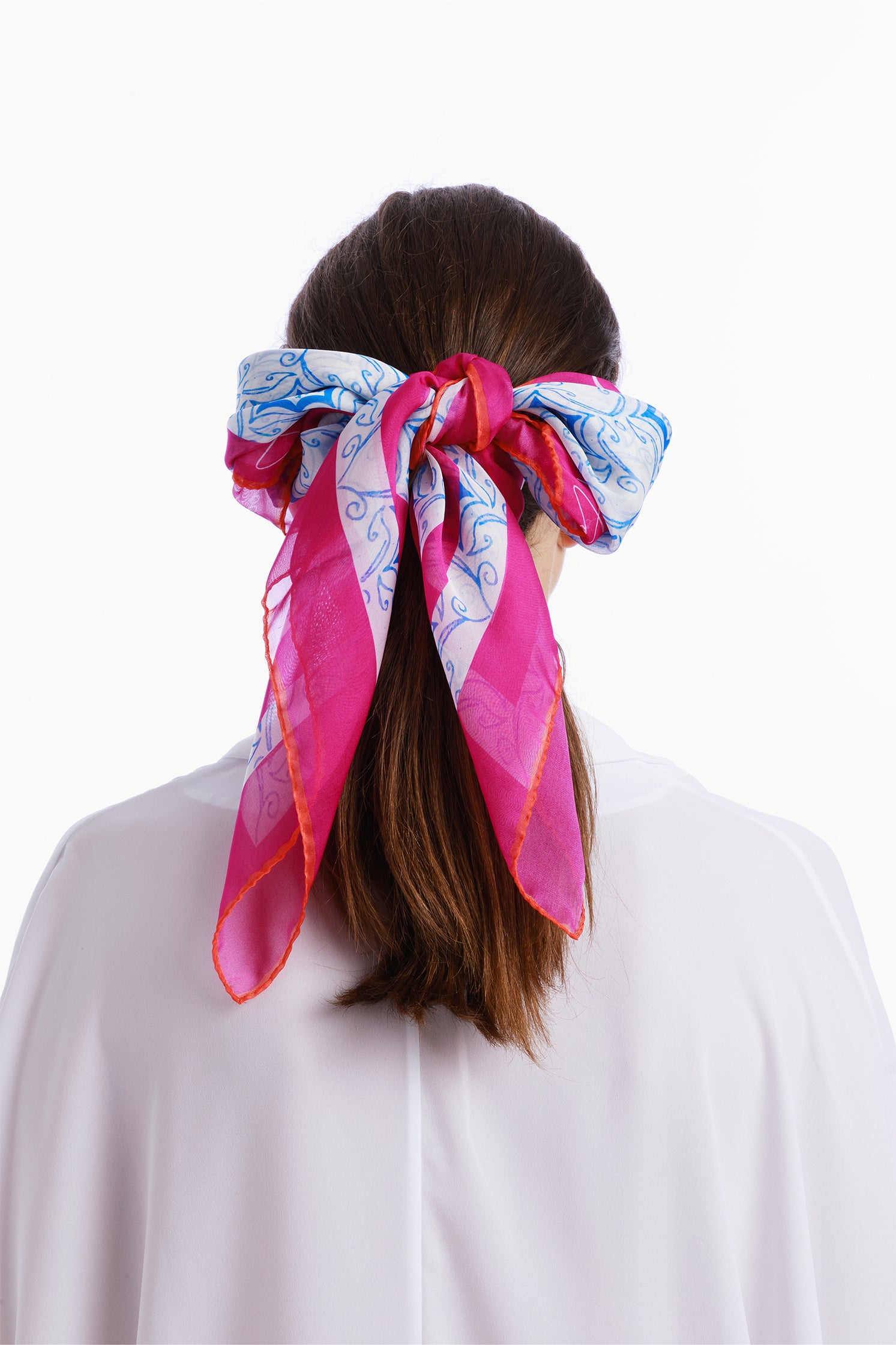 Back view of the lightweight 90x90 cm silk chiffon scarf worn on the head by a model featuring a dynamic design inspired by the force of a typhoon, with flowing shapes and vibrant movement.