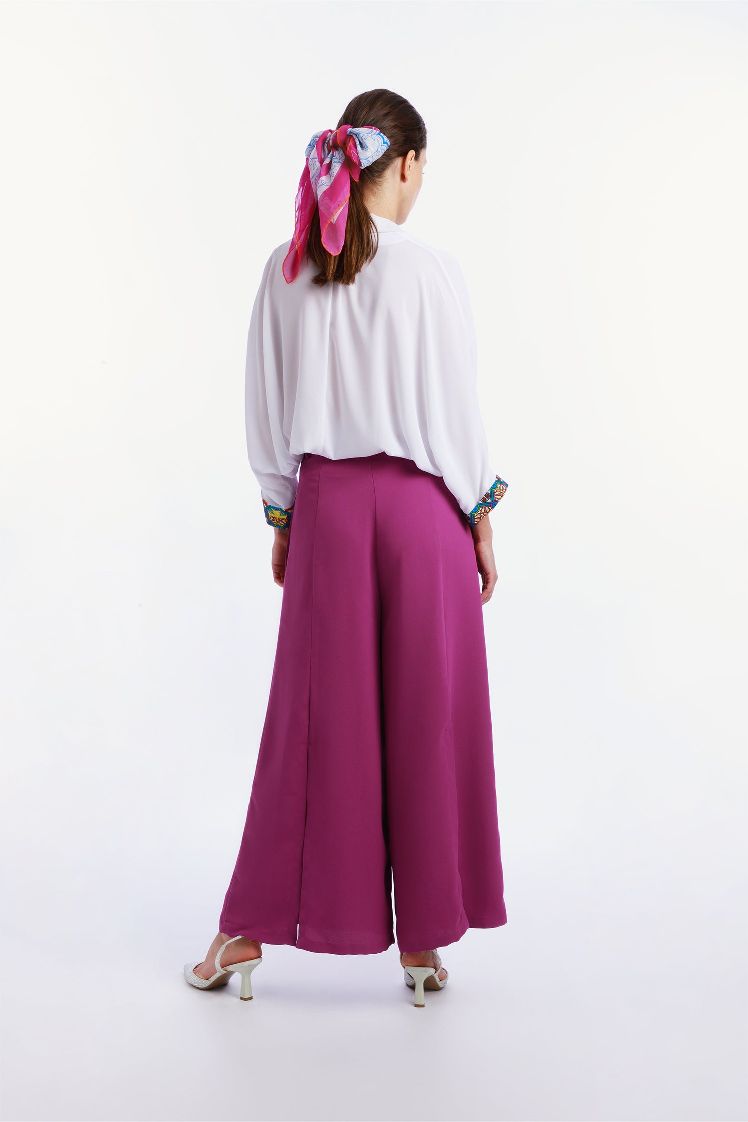 Back view of the lightweight 90x90 cm silk chiffon scarf worn on the head by a model featuring a dynamic design inspired by the force of a typhoon, with flowing shapes and vibrant movement.