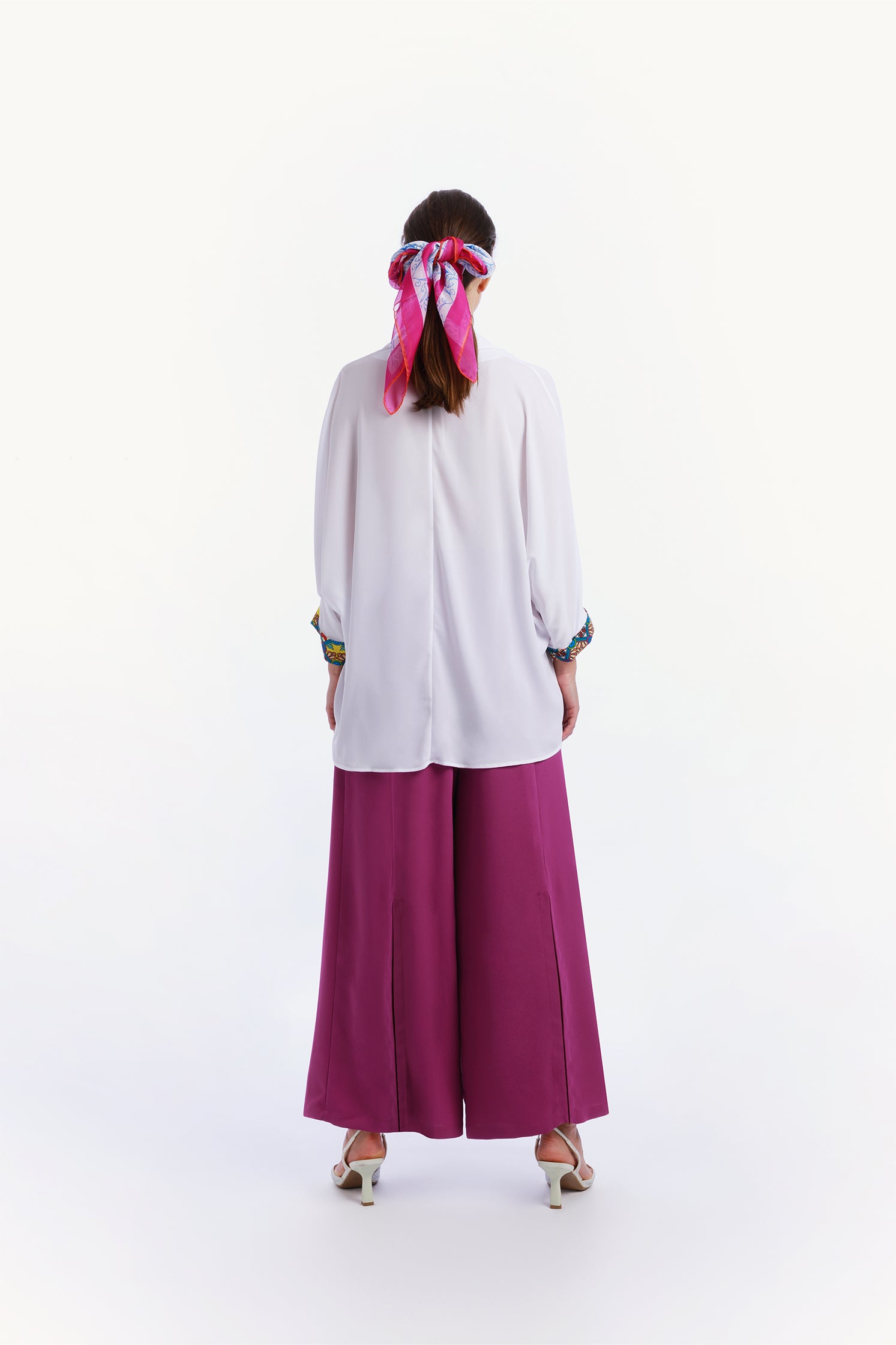 Back view of the lightweight 90x90 cm silk chiffon scarf worn on the head by a model featuring a dynamic design inspired by the force of a typhoon, with flowing shapes and vibrant movement.