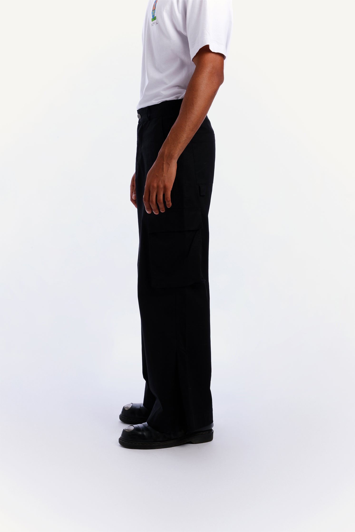 Side view of the unisex black cargo pants worn by a model with relaxed fit and side patch pockets.