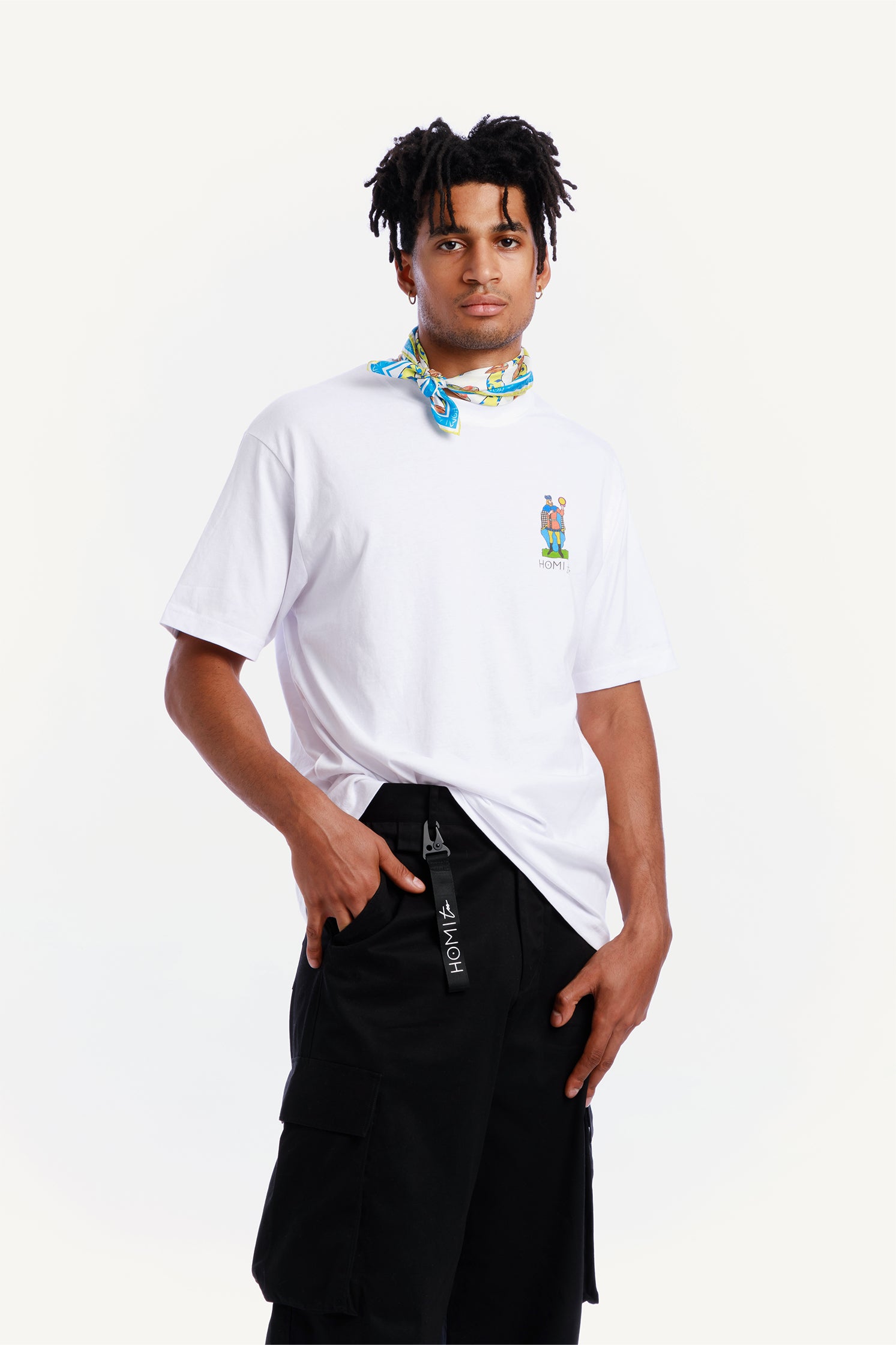 Close-up of the of the unisex black cargo pants worn by a model with relaxed fit and side patch pockets paired with a black keychain featuring the "Homi Too" logo in white lettering.