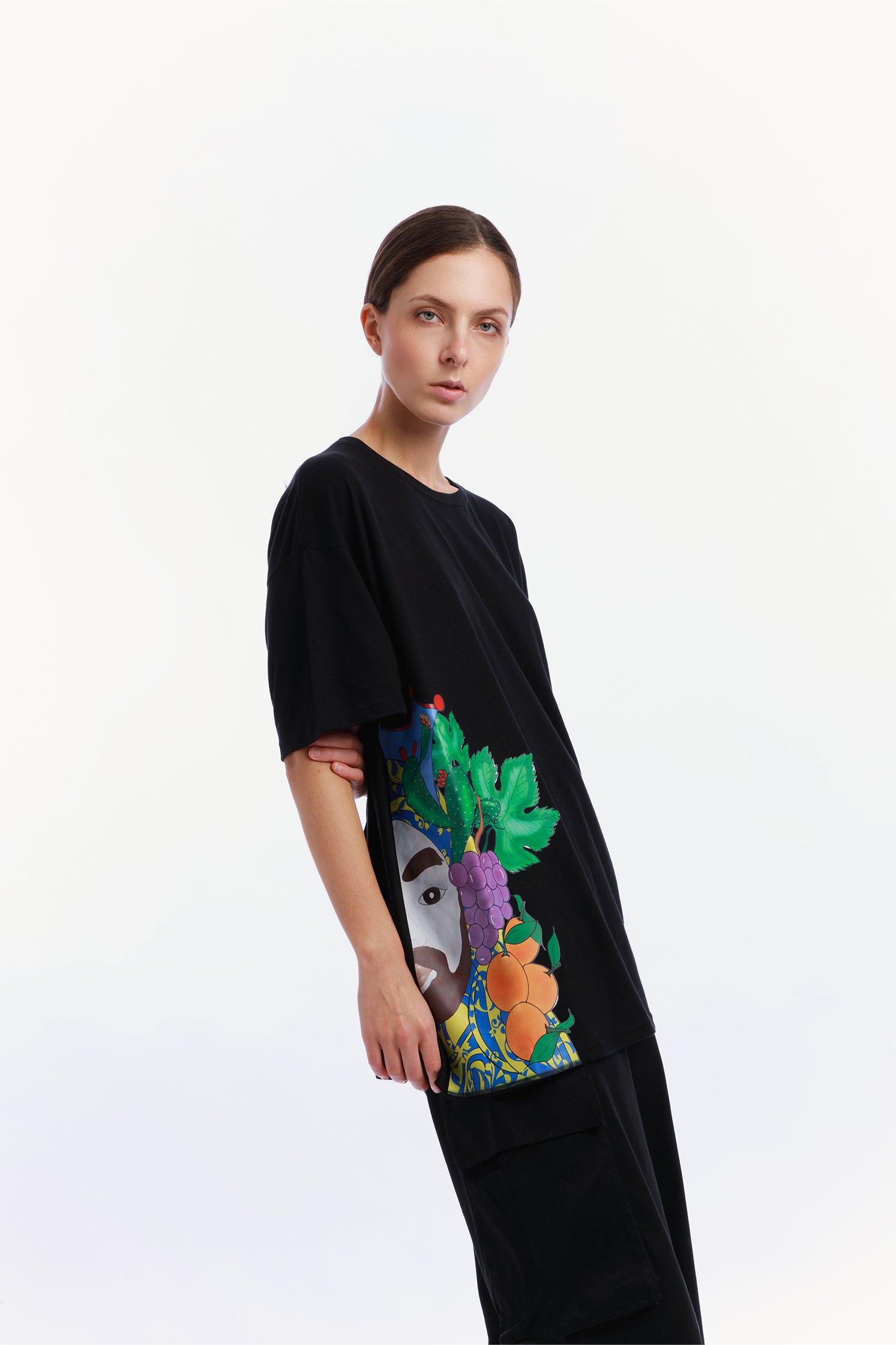 Side view of the black oversized unisex T-shirt made of 100% high-quality cotton, worn by a model, featuring a modern cut and a unique hand-painted "Testa di Moro" graphic on the right side.