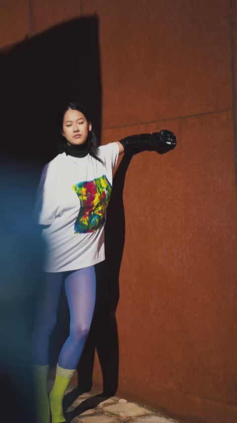 White unisex oversized T-shirt worn by a model, with central multicolor square hand-made using an exclusive silicone technique.
