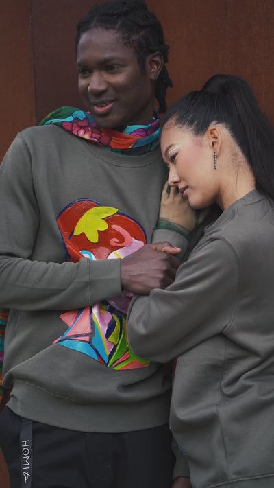 Unisex oversized green sweatshirt worn by two models, featuring a hand-crafted raised silicone abstract geometric face print, creating a three-dimensional and tactile effect